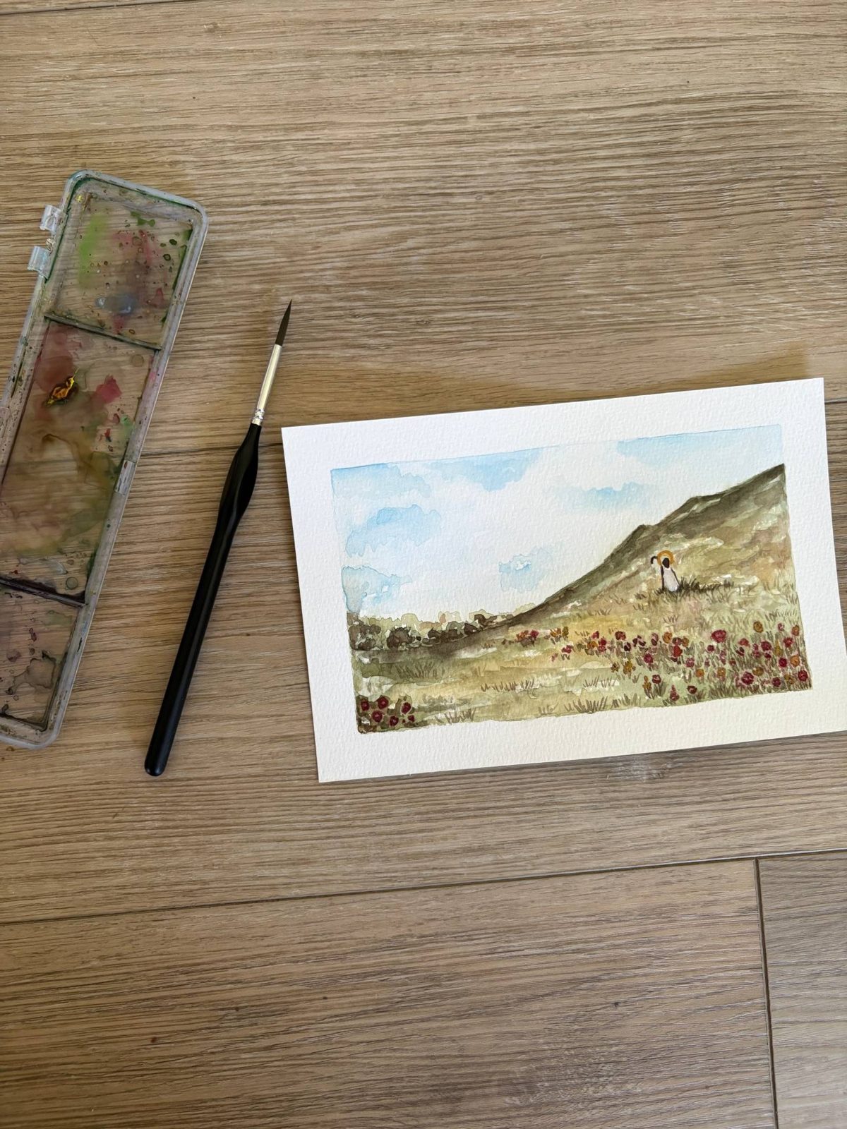 Watercolor of a dog on a wildflower hillside